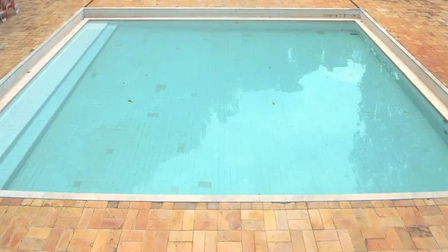 Eau de piscine limpide et turquoise bordée de margelles.
